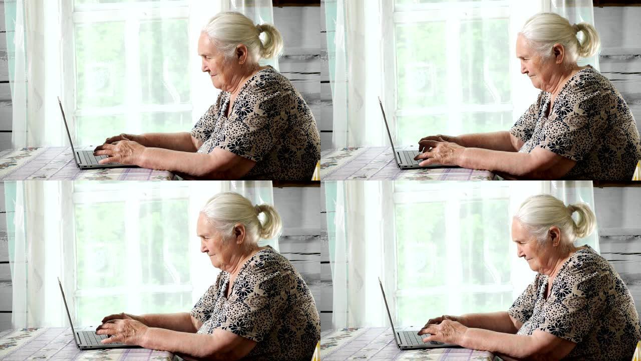 老年妇女坐在靠窗的桌子旁，在笔记本电脑上打字。慢动作
