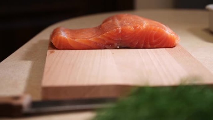 切菜板上的生去皮三文鱼。桌子上有新鲜三文鱼的鱼片。