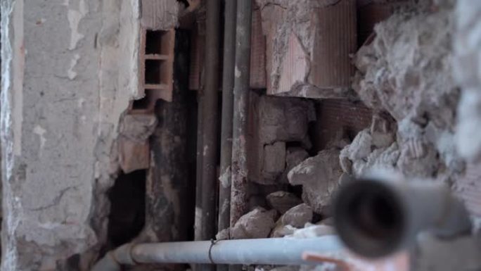旧废弃房屋的混凝土墙内长生锈的铜管，在建筑施工中破坏了砖墙和管子。供水系统或燃气管道，施工现场维修工