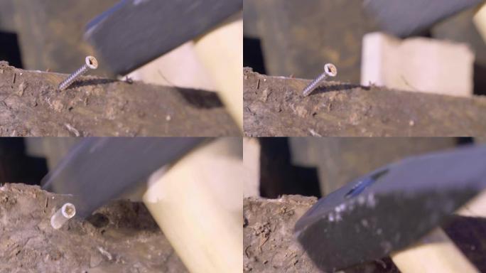 锤子在施工现场用不锈钢钉将其插入肮脏的木板中，并关闭。自攻螺丝因使用不当而弯曲
