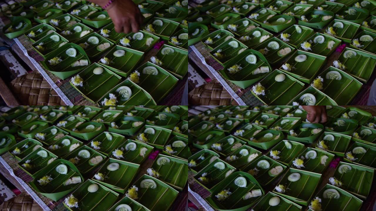 hand用棕榈叶，鲜花和蔬菜准备印度教的供品巴厘岛