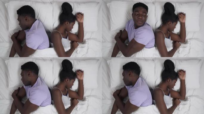特写非洲夫妇背靠背躺在床上的肖像。在关系中争吵。男人试图和女朋友说话，但女孩拒绝了。