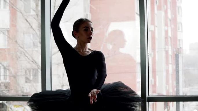 芭蕾舞演员以城市为背景，舞动动人。穿着黑色短裙和尖头鞋。芭蕾舞中的黑天鹅形象。慢动作。