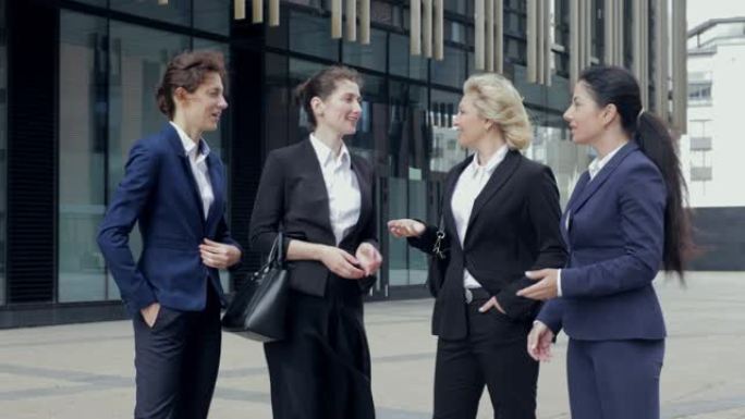 穿着西装的女性商务人士站在那里，看着镜头讨论着生意。他们都在中央商务区工作