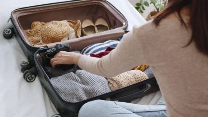 女人手工包装行李箱，包括面罩和消毒剂，保护冠状病毒新型冠状病毒肺炎，旅行新常态概念