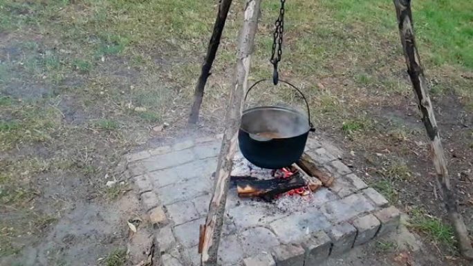在户外用铸铁大锅做饭。在火上做饭。火上的大锅里的食物。在大锅上烹饪自然界中的食物