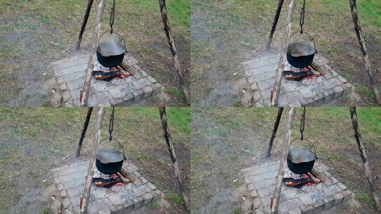 在户外用铸铁大锅做饭。在火上做饭。火上的大锅里的食物。在大锅上烹饪自然界中的食物