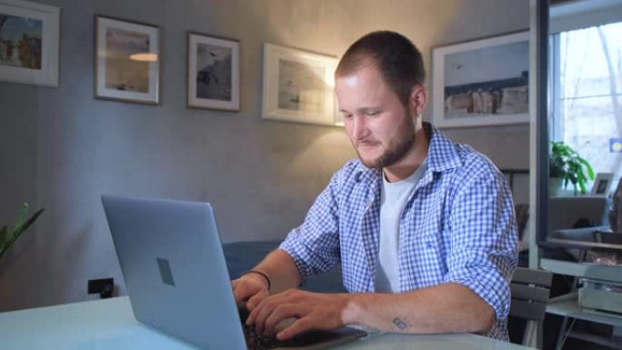 男人正在工作打字在黑暗的夜晚在家庭办公室使用笔记本电脑。社交媒体facebook浏览。