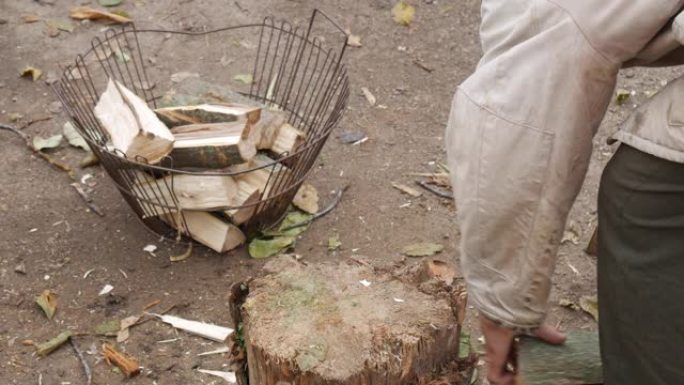 一个贫穷的俄罗斯村庄的爷爷用树桩上的斧头砍柴。秋天的村庄院子。为冬天收割柴火。