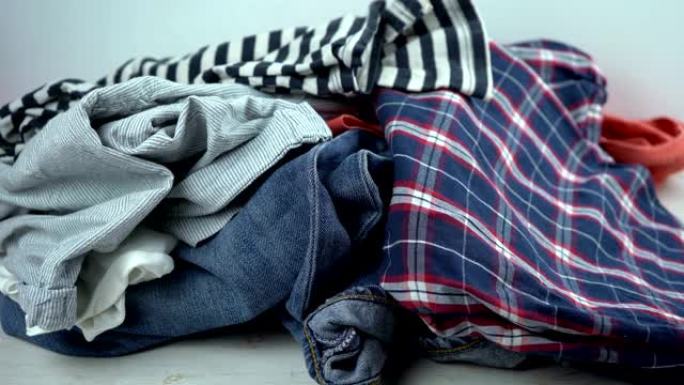 牛仔裤，睡衣，衬衫掉在桌子上。捐赠或脏衣服的概念