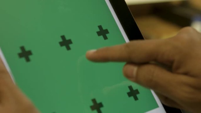 男性双手使用平板电脑，屏幕在绿色背景和跟踪点。
