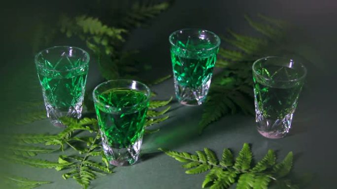 烈性酒。绿色苦艾酒的铅杯。森林蕨类植物和魔法阴影