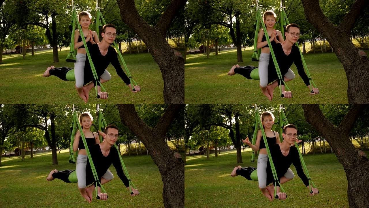 教练和孩子在城市公园练习反重力瑜伽。慢动作。