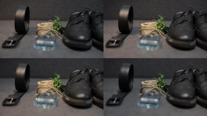 新郎的婚礼细节。新郎香水，皮带，鞋子和结婚戒指躺在沙发上