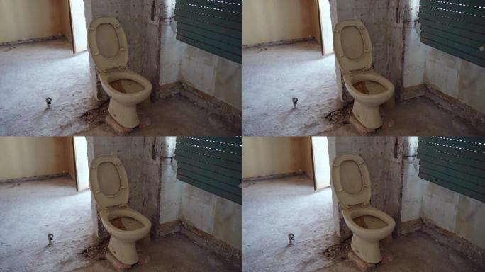 废弃房屋中的老生锈肮脏的黄色厕所，陶瓷堵塞的厕所靠在剥皮的墙上。室内照片被摧毁的公寓，浴室被毁，厕所