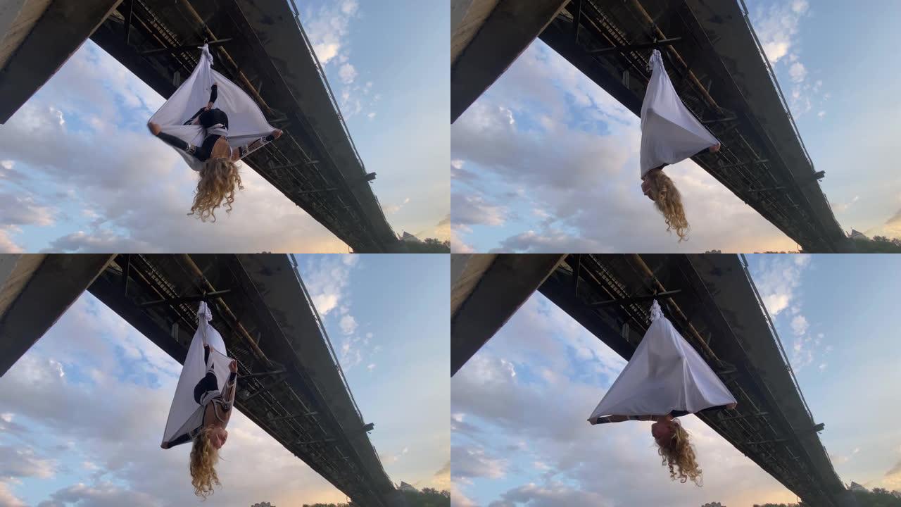 女童空中飞人表演杂技技巧，悬挂空中丝绸并用织物挥舞。
