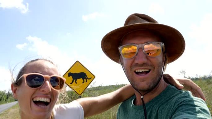 年轻夫妇在佛罗里达黑豹警告标志附近空荡荡的高速公路上自拍