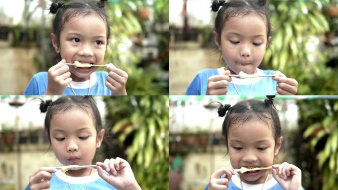 快乐的亚洲女孩在家后院吃冰淇淋，生活方式理念。