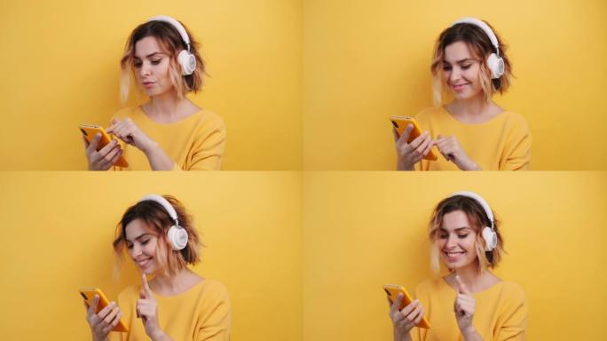 穿着白色耳机的快乐微笑的年轻性感女孩的肖像在智能手机中寻找好音乐，发现，在孤立的黄色背景上跳舞。乐事