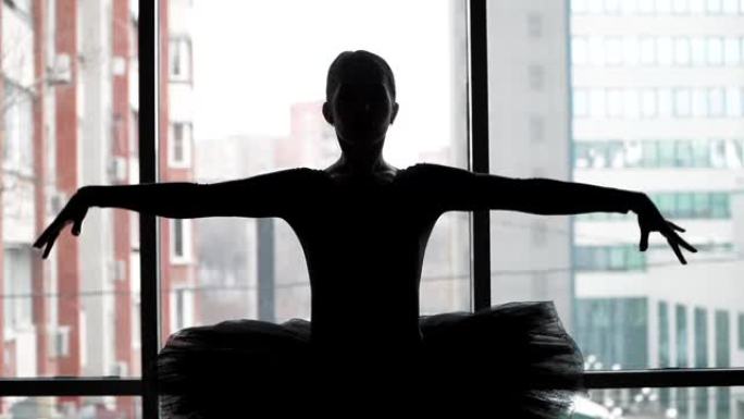 芭蕾舞演员的剪影在城市的背景下动人的舞蹈。穿着黑色短裙和尖头鞋。芭蕾舞中的黑天鹅形象。慢动作。