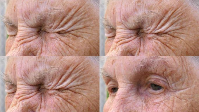 高级祖母的肖像带着悲伤的景象向远处望去。年迈的奶奶的特写强烈地拧紧了她灰色的眼睛。成熟女人悲伤的面部