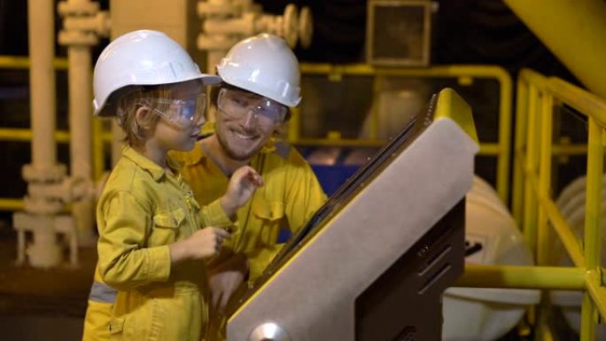 一个年轻人和一个小男孩都穿着黄色的工作服，戴着眼镜，戴着头盔，在工业环境中，石油平台或液化气厂看着屏