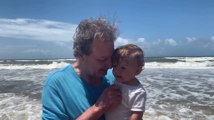 祖父和婴儿在海滩上建立联系，模仿祖父母的婴儿