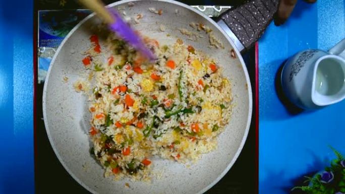 准备一顿饭。蔬菜炒饭在煎锅里用勺子搅拌。