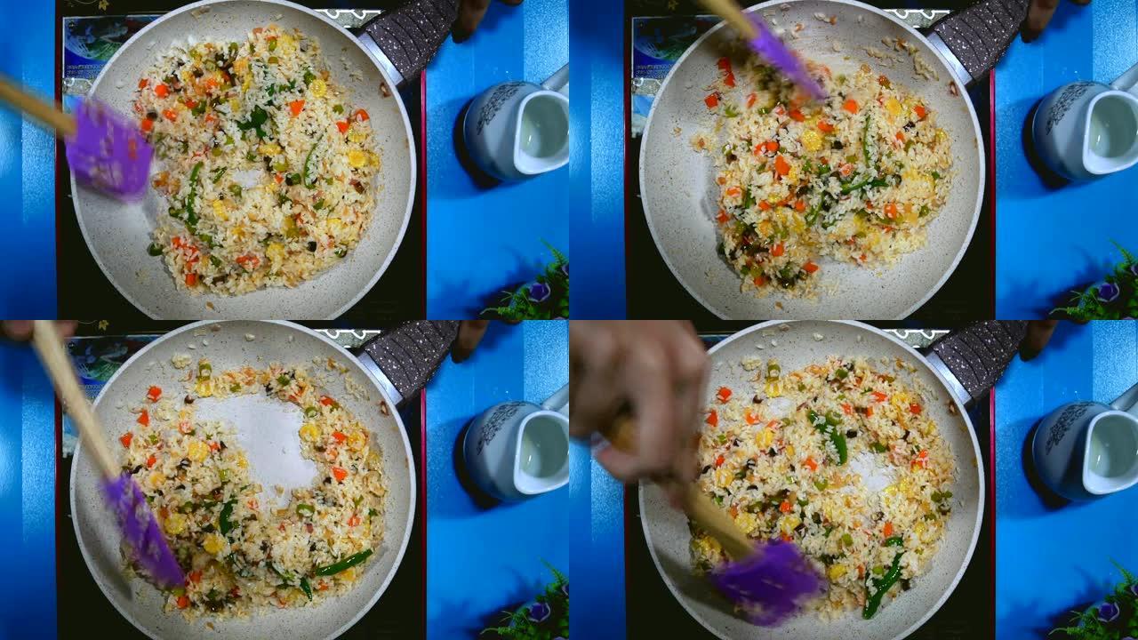 准备一顿饭。蔬菜炒饭在煎锅里用勺子搅拌。