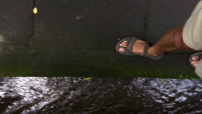 一名男子沿着巴厘岛乌布村的水渠行走。在电话上拍摄