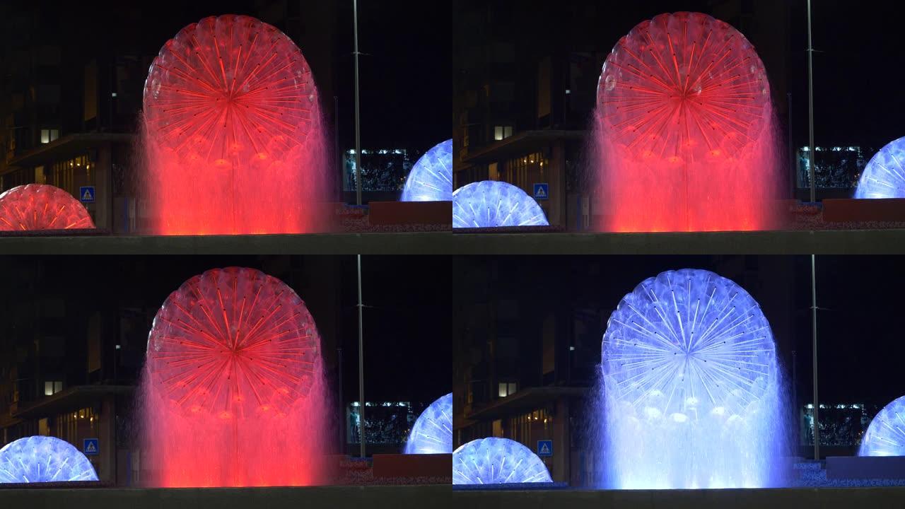 带有红色和蓝色水球的现代喷泉在夜晚闪耀