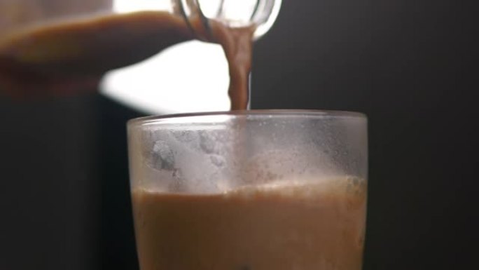 将咖啡倒入加冰的玻璃杯中。慢动作用咖啡填充玻璃