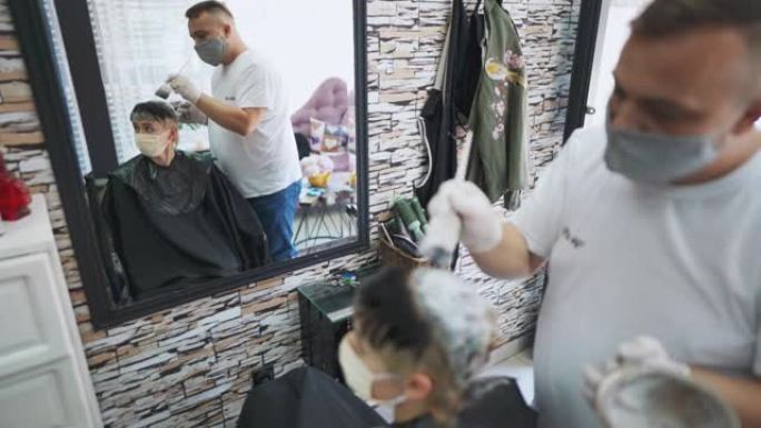 男性发型师从事客户头发的工作并在沙龙中使用染发剂
