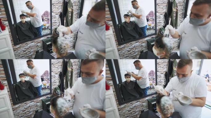 男性发型师从事客户头发的工作并在沙龙中使用染发剂