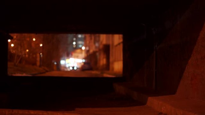 黄昏时隧道尽头有发光路灯的深色石头网关。