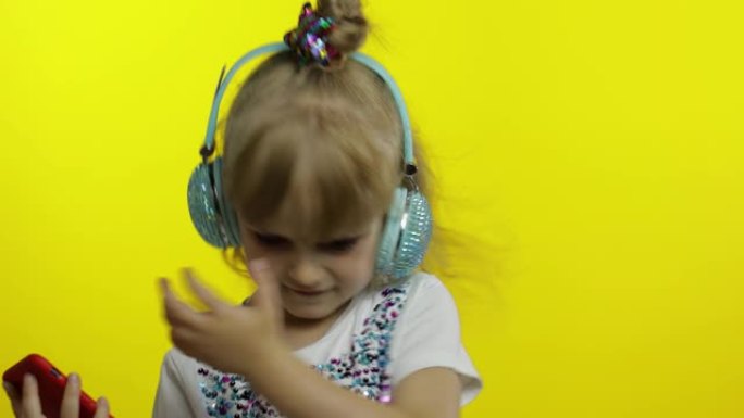 孩子用智能手机跳舞，用耳机听音乐。小女孩跳舞，有匈奴