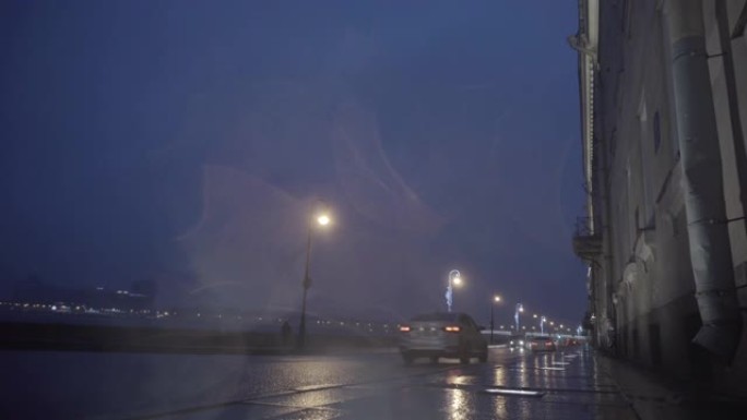 秋天下雨的城市街道在晚上，夜间在潮湿的道路上下雨，路灯在水坑中反射。动。美丽的路堤和照明桥，第一人称