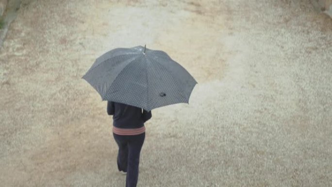 大雨下穿过花园道的妇女