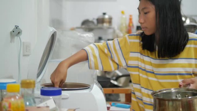 亚洲女孩在家厨房煮饭，女孩帮妈妈准备食物。