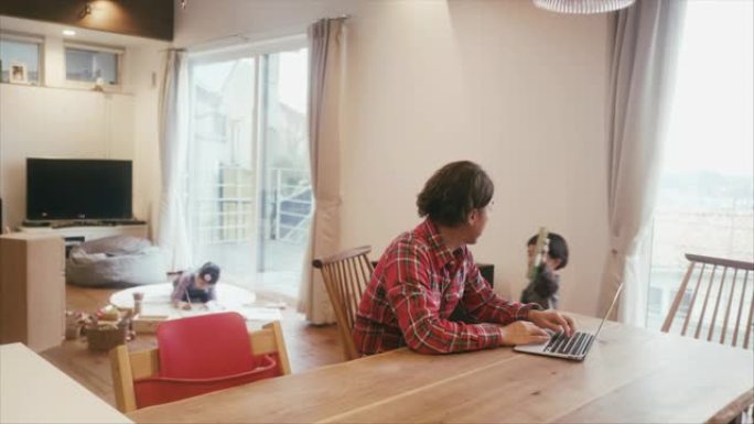 日本男子在家工作，孩子们在客厅玩耍