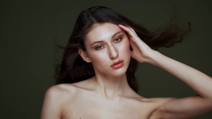 一个美丽的年轻女子，有着长长的黑色卷发，乳房肖像，裸露的肩膀。美丽的自然皮肤。红唇和优雅的手。女孩在