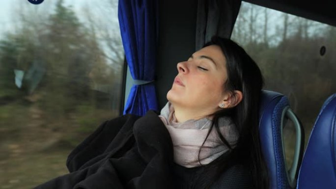 女乘客在公路上旅行时在公共汽车上睡着了。睡在公共汽车窗户旁边的女孩