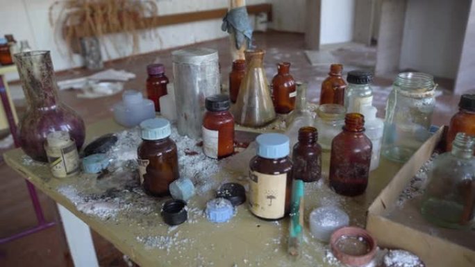 玻璃瓶，试管，烧瓶和杯子放在旧化学实验室的桌子上。建筑物在战争或地震后被摧毁。