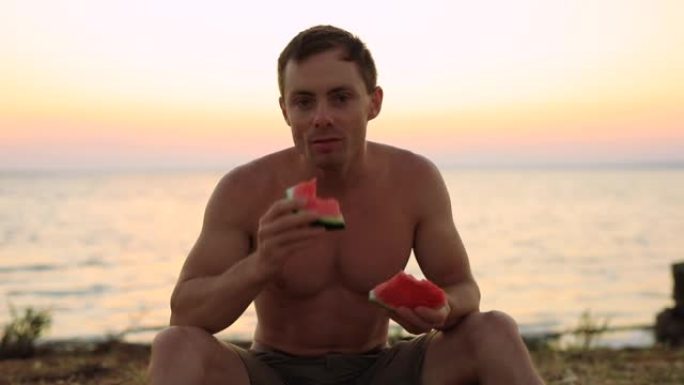 自信的男人坐在海边吃西瓜