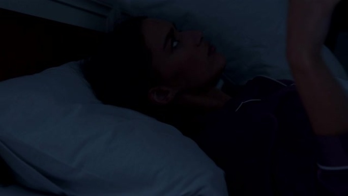 深夜在床上用枕头遮住耳朵的年轻女性