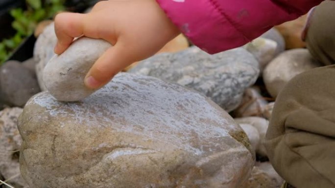 孩子用一块石头打另一块石头的特写