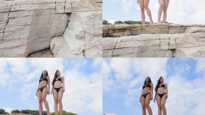 两名穿着比基尼的年轻女子站在岩石上