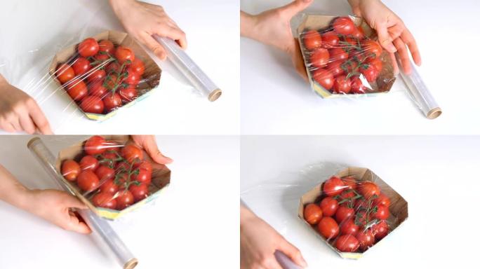女人用食物薄膜在白色桌子上储存食物。包装产品用透明聚乙烯食品薄膜卷。樱桃番茄在一次性塑料包装慢动作视
