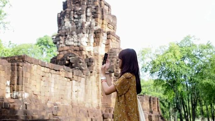 亚洲妇女使用手机拍摄泰国古代废墟的照片并上传到社交媒体网络。