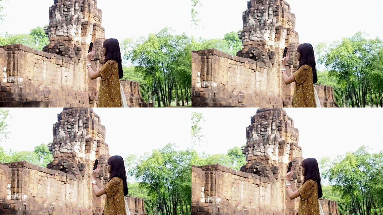 亚洲妇女使用手机拍摄泰国古代废墟的照片并上传到社交媒体网络。